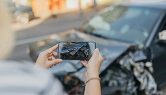 person in car crash taking photos of car damage